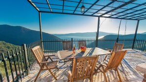 Un espace extérieur abrité, avec une table et des chaises, offrant une vue sur un paysage montagneux.