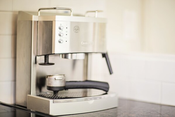 Una cafetera moderna con pantalla digital y panel de control, ubicada sobre una encimera de cocina.