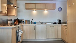 A modern kitchen with wooden cabinets, stainless steel appliances, and a built-in oven. - Clarence Court - Free Parking, W-Fi & Netflix (Newcastle)