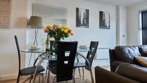 A modern dining area with a glass table, black chairs, and a vase of flowers. - Clarence Court - Free Parking, W-Fi & Netflix (Newcastle)
