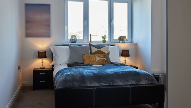 A bedroom with a bed, two bedside tables, a window with a view, and a wall-mounted artwork. - Clarence Court - Free Parking, W-Fi & Netflix (Newcastle)