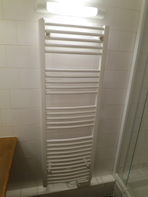 A bathroom with a white towel rack, a glass shower enclosure, and white tiled walls. - Tignes Les Brevieres, charming 3 rooms Direct lifts (Tignes)