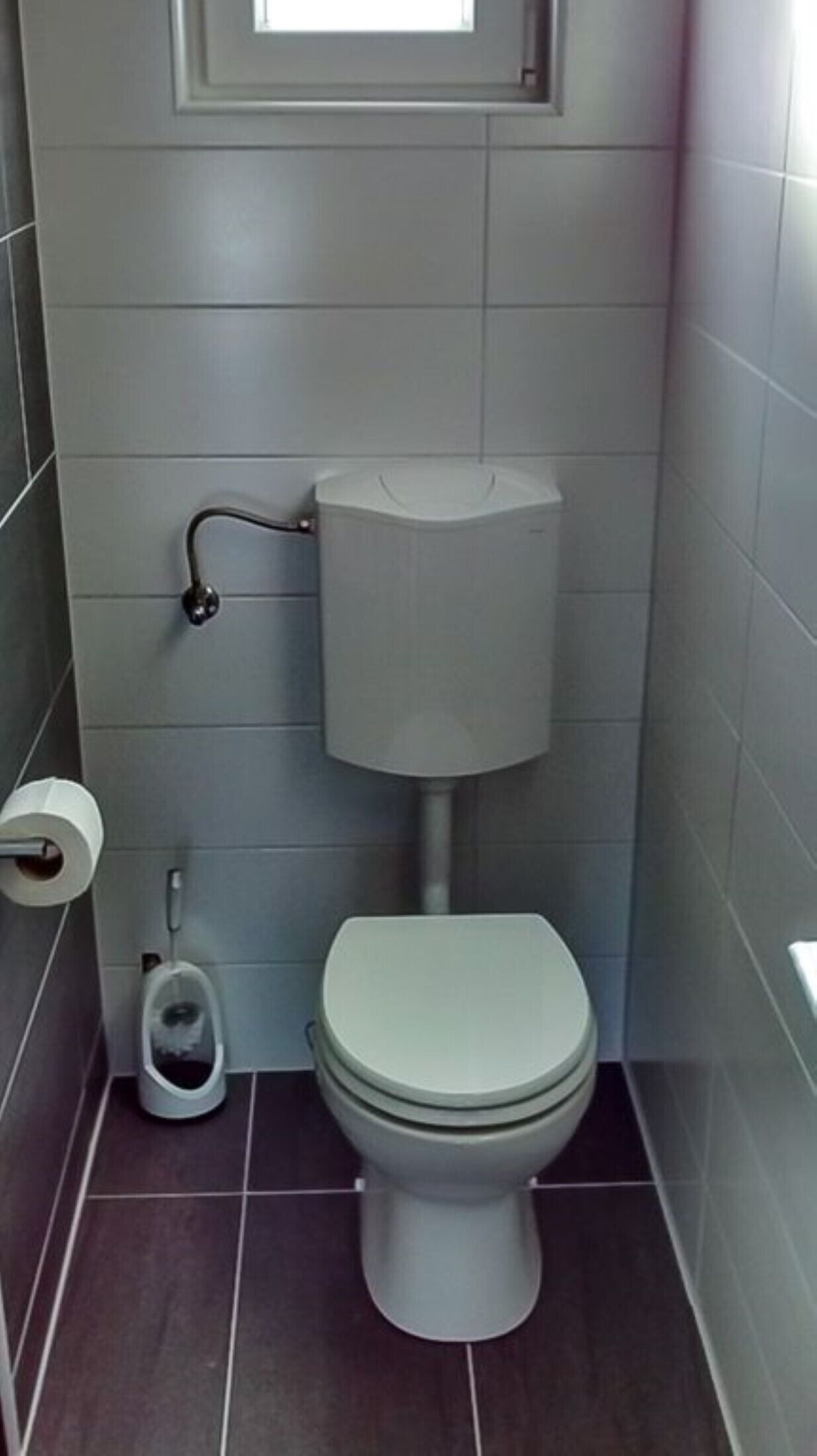 Et lille, kompakt badeværelse med toilet, bidet og toiletpapirholder.