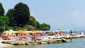 Une plage avec une eau claire, des parasols et des gens qui se détendent.