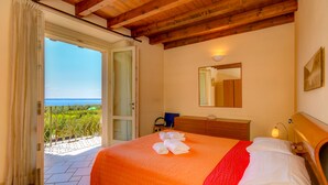 Une chambre à coucher avec un lit, une commode, un miroir et une vue sur la mer.