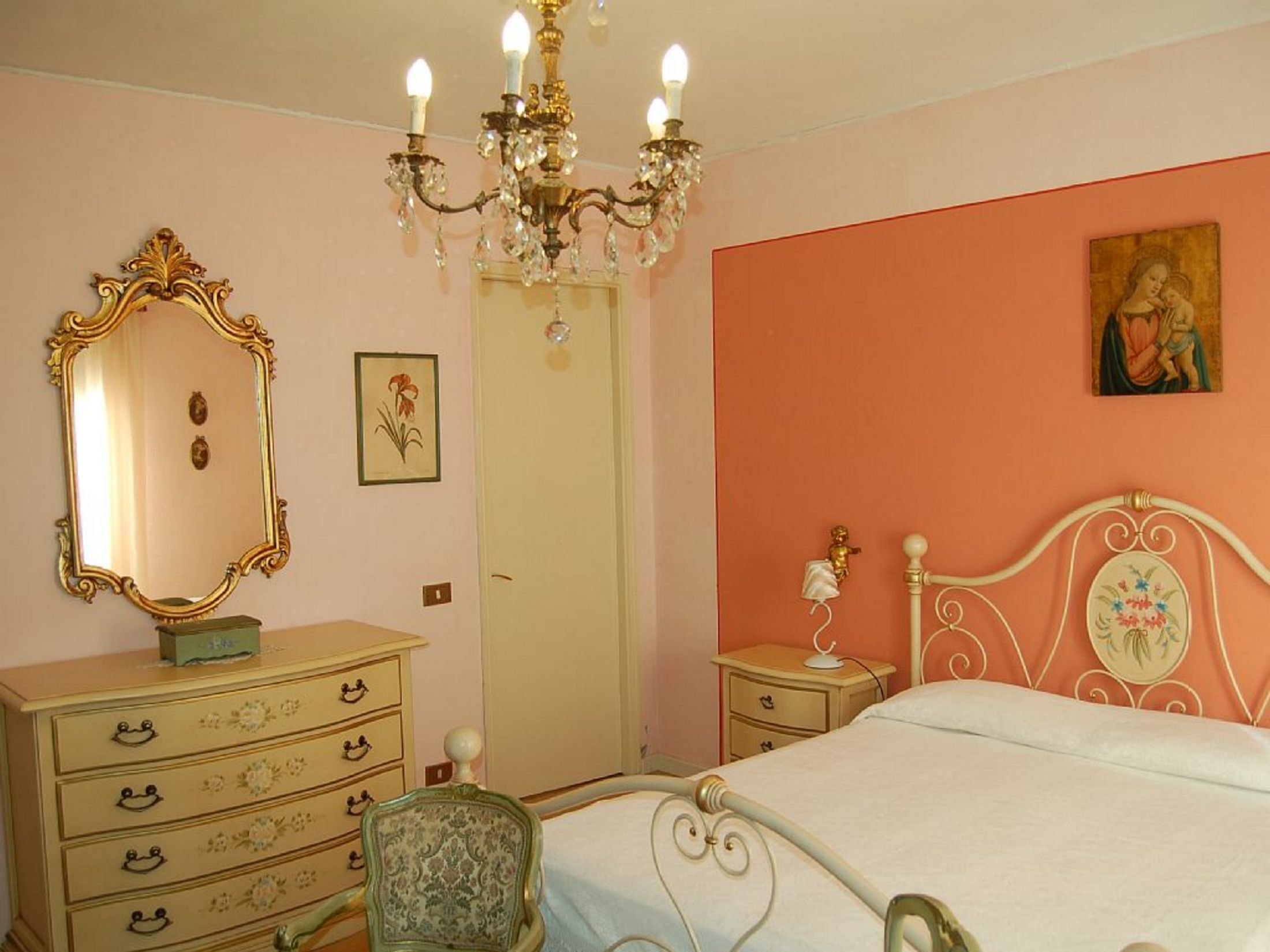 Ein Schlafzimmer mit Bett, Kommode, Stuhl und einer Chandelier.