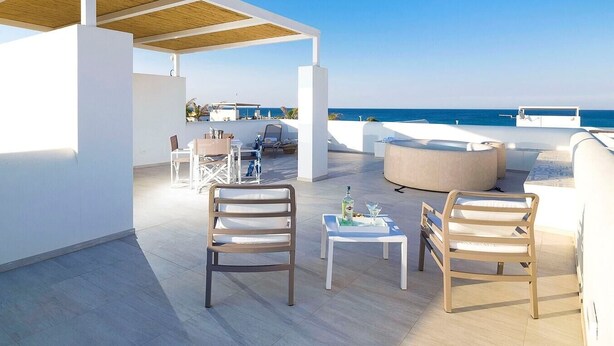 A rooftop terrace with white furniture, a wooden table, and a view of the sea. - Marza Residence – Rosa, with private pool (Reitani)