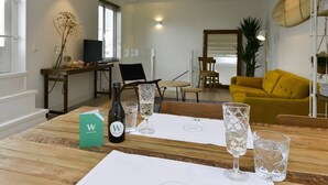Zona pranzo con tavolo in legno apparecchiato per due, una bottiglia di vino e un menu.