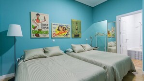 Una habitación con dos camas, una lámpara y carteles en la pared.