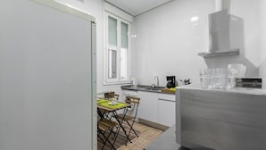 Una cocina moderna con armarios blancos, horno empotrado y ventana con persianas.