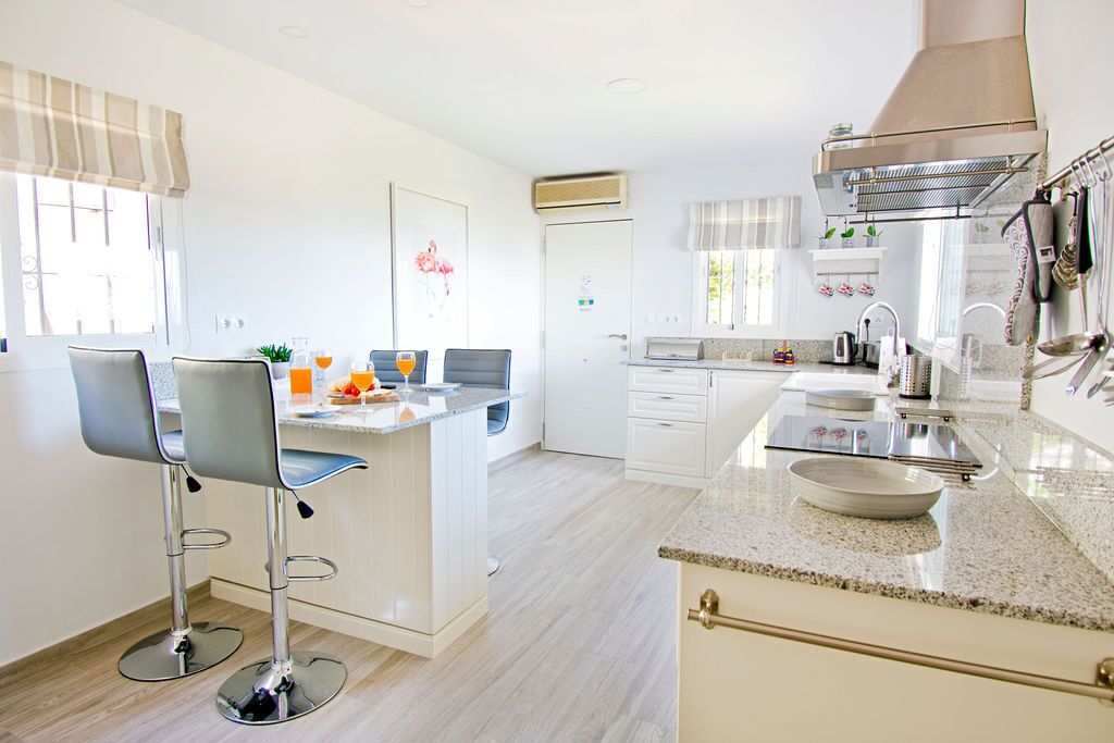 Een moderne keuken met een centraal eiland, barstoelen, een ingebouwde oven en een roestvrijstalen afzuigkap.