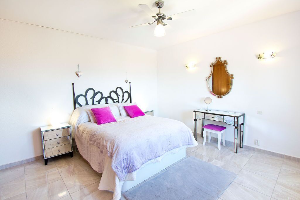 A bedroom with a bed, nightstands, a desk, and a chair.