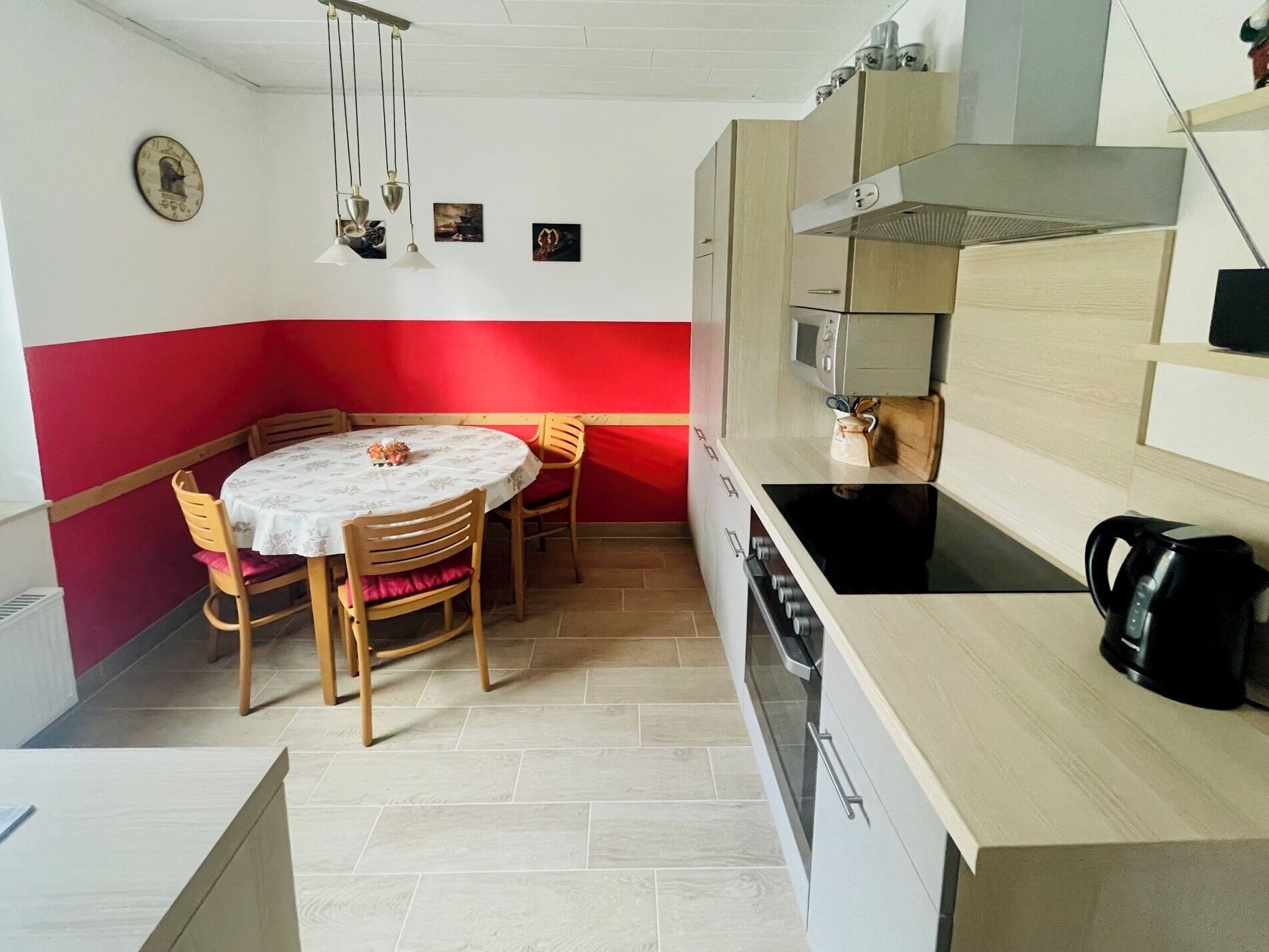 Cozinha compacta com área de refeições, com uma mesa redonda, cadeiras, micro-ondas e fogão.