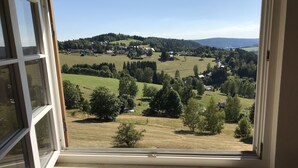 A view from a window overlooking a rural landscape with houses, trees, and rolling hills.