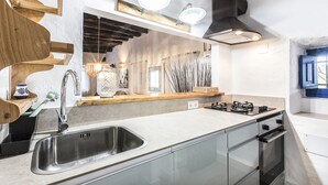 Una cocina moderna con un lavamanos de acero inoxidable, detalles de madera y un horno empotrado.