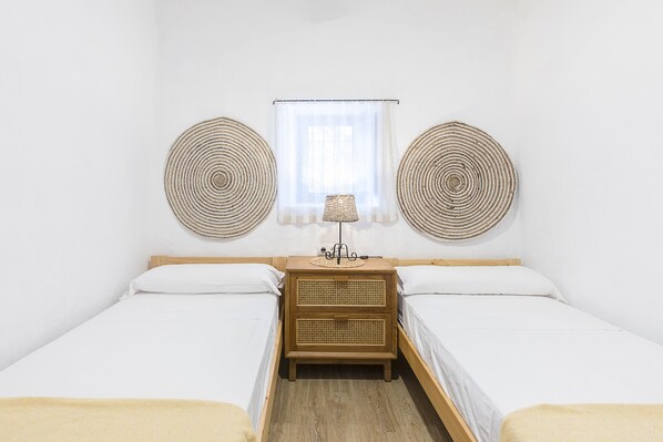 A room with two single beds, a wooden nightstand with a lamp, and two wall-mounted circular decorations.