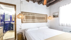 Un dormitorio con una cama, cabecera de madera, un espejo y una ventana con cortinas.