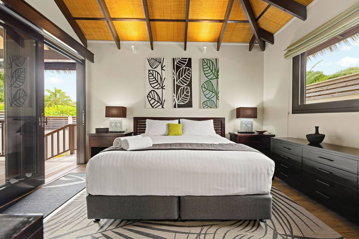 A bedroom with a bed, nightstands, a dresser, and artwork on the wall.