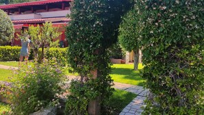A garden pathway leading to a building with a red roof, surrounded by lush greenery and flowering plants. - villas just by the sea (Santa Maria di Ricadi)
