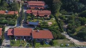 An aerial view of a coastal resort with multiple red-roofed buildings, a sandy beach, and clear turquoise waters. - villas just by the sea (Santa Maria di Ricadi)
