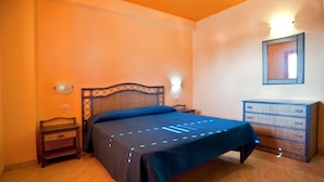 A bedroom with a bed, bedside tables, a dresser, and wall-mounted lights. - villas just by the sea (Santa Maria di Ricadi)