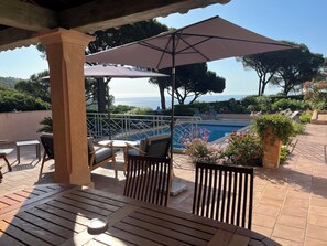 Ein überdachter Außenbereich mit Pool, Stühlen und Sonnenschirmen.