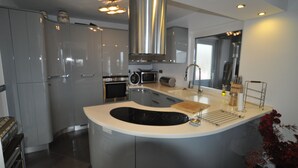 A modern kitchen with a central island, stainless steel appliances, and a large overhead vent. - Luxury villa with heated pool in Puerto de la Cruz (Puerto de la Cruz)
