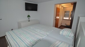 A bedroom with a bed, a TV mounted on the wall, and a small desk with a lamp. - Luxury villa with heated pool in Puerto de la Cruz (Puerto de la Cruz)