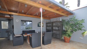 An outdoor patio with a wooden ceiling, wicker furniture, a potted plant, and a cabinet with glassware. - Luxury villa with heated pool in Puerto de la Cruz (Puerto de la Cruz)