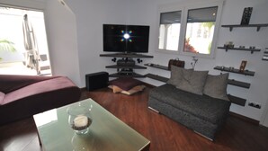 A modern living room with a flat-screen TV, a grey sofa, a red couch, and a glass coffee table. - Luxury villa with heated pool in Puerto de la Cruz (Puerto de la Cruz)