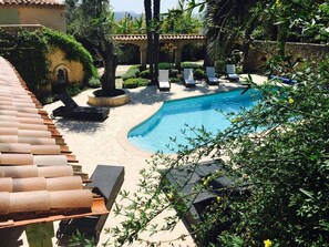 En swimmingpool med solstolar, en pergola och en stenmur.