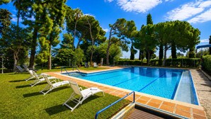 A swimming pool with clear blue water, surrounded by grass and trees.