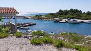 Un puerto costero con barcos amarrados, un pabellón y terreno rocoso.