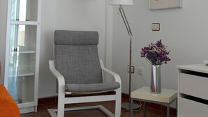 A modern room with a grey upholstered chair, a floor lamp, a small table with a vase of flowers, and a white cabinet. - Modern Oceanfront Penthouse Apartment. Very Spacious. Big Sunbathing Terrace. (El Medano)