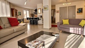 Un salon moderne comprenant un canapé, une table basse et un coin repas avec des chaises.