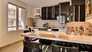 Une cuisine moderne avec des meubles de couleur noire, un îlot central doté de tabourets et une fenêtre qui laisse entrer la lumière naturelle.