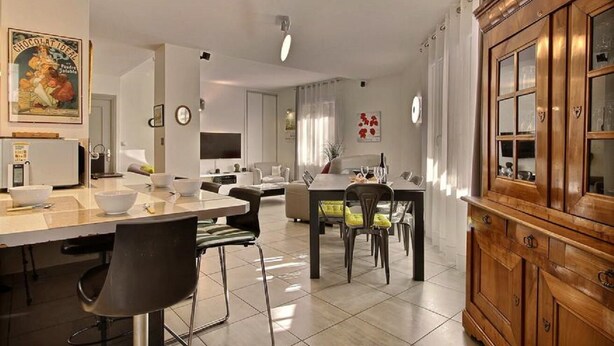 Une cuisine moderne avec un coin repas, comprenant un meuble en bois, un réfrigérateur et une table à manger avec des chaises.
