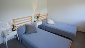 Un dormitorio con dos camas individuales, una mesita de noche con lámpara y una pequeña mesa con un jarrón de flores.