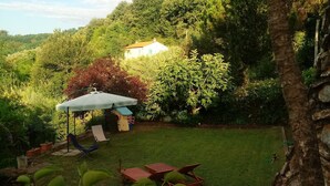 Un patio trasero con césped, una casa blanca al fondo y una palmera.
