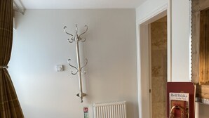 Une pièce avec un plancher en bois, un radiateur, un porte-manteau, un extincteur, une armoire en bois et un livre intitulé « Brill se promène dans le Peak District ».