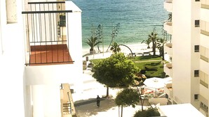 Un edificio alto con balcón que da a una playa y al océano.