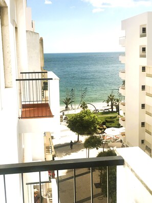 A high-rise building with a balcony overlooking a beach and ocean.