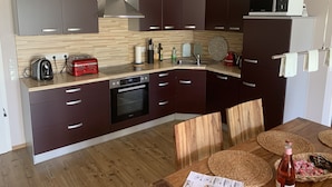 A modern kitchen with dark cabinets, a stainless steel range hood, a built-in oven, a microwave, and a sink. - Comfortable holiday apartment within walking distance of the beach, Fehmarn Golf Park and surfing area  (Fehmarn)