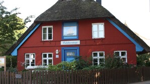 Een rood gebouw met een blauwe deur en ramen, omgeven door een houten hek.