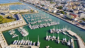 An aerial view of a marina with numerous boats docked, surrounded by a cityscape with buildings and a coastline. - Quinta da Liberdade: Spacious Cottage (4 persons) (Montinhos Da Luz)
