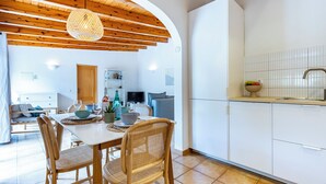 A modern kitchen with white cabinets, a wooden ceiling, and a dining area with a table and chairs. - Quinta da Liberdade: Spacious Cottage (4 persons) (Montinhos Da Luz)