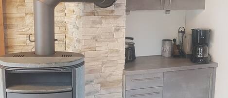 A modern kitchen with a stone accent wall, a built-in stove, and a coffee maker.