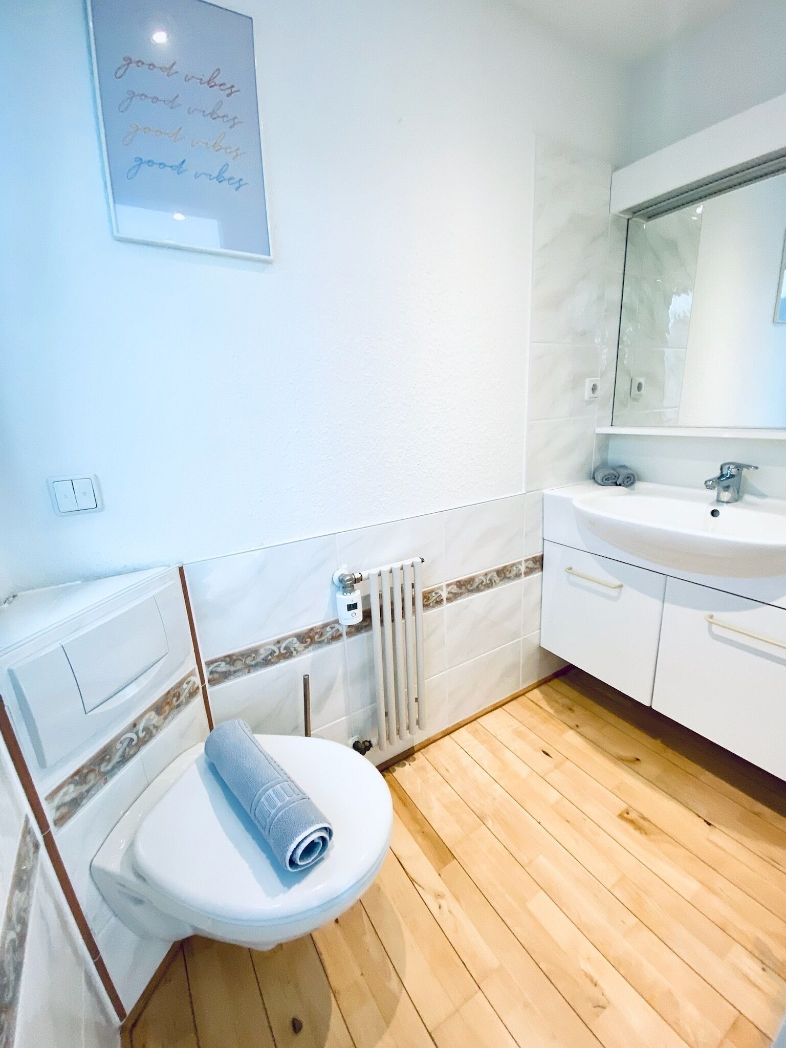Ein Badezimmer mit Toilette, Waschbecken, Spiegel und Heizkörper.
