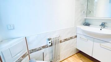Ein Badezimmer mit Toilette, Waschbecken, Spiegel und Heizkörper.