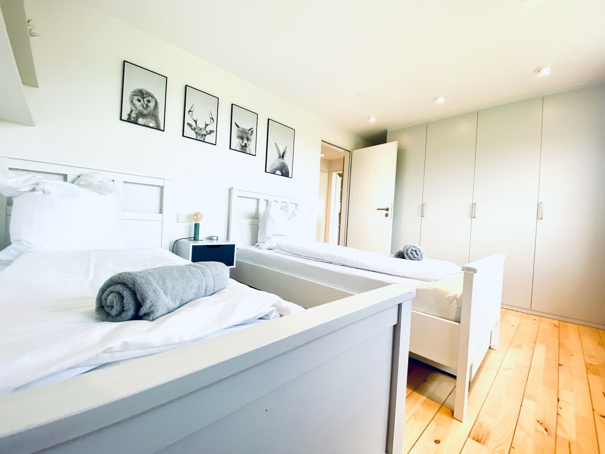 Una camera da letto moderna con due letti, un armadio e quadri con animali appesi al muro.